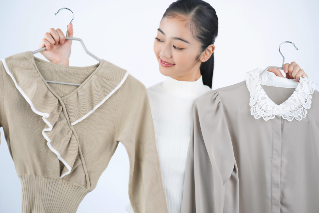 手持ちの服からどちらがいいのかファッションコーディネートに悩む様子の女性