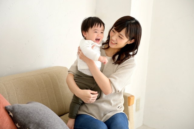 ソファーで抱っこされて上機嫌の小さな男の子と笑顔のママ