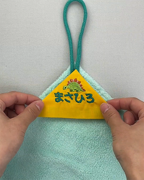 タオルの角にあわせて刺しゅうした布を置きます